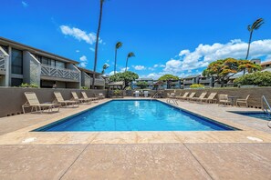 A swimming pool with lounge chairs and a building with a balcony in the background. - Beautiful Ocean View 2 Bedroom Condo 1 Min Walk to Beach! (Kihei)