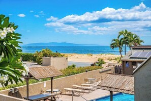 Área de piscina en la azotea con sillones de descanso y vista a la playa y al océano.