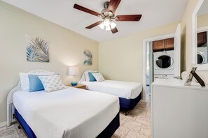A hotel room with two beds, a ceiling fan, a washing machine, and a small table with a lamp. - Beautiful Ocean View 2 Bedroom Condo 1 Min Walk to Beach! (Kihei)