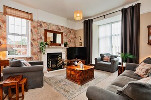 Ein Wohnzimmer mit Kamin, zwei Sofas, einem Couchtisch und einem Fernseher.