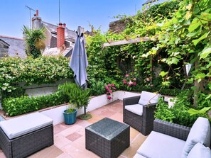 A patio with wicker furniture, a pergola covered with climbing plants, and a stone wall. - Holiday Stay With Sea Glimpse (Torpoint)