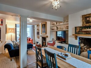 A cozy living room with a fireplace, a television, and a dining area with chairs and a table. - Holiday Stay With Sea Glimpse (Torpoint)