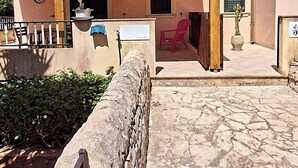 A covered outdoor area with a stone wall, a wooden bench, and a potted plant. - The Residences 3 (Marina di Modica)