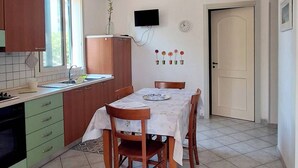 A kitchen with a dining table, cabinets, and a television. - The Residences 3 (Marina di Modica)