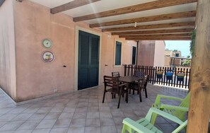 Un espace extérieur aménagé en terrasse, avec une table et des chaises en bois, un sol carrelé et une rambarde.