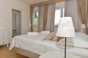 Une chambre à coucher avec un lit, une table de chevet, une lampe et une fenêtre avec des rideaux.