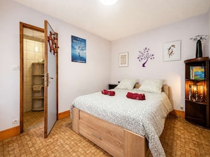 Ein Schlafzimmer mit Bett, Kleiderschrank, Spiegel, einem Poster und einem Bücherregal.