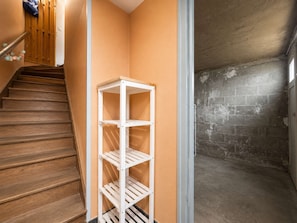Un angolo con un mobile contenitore bianco, una scala in legno e un muro in mattoni.