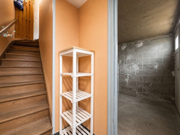 A corner with a white shelving unit, a wooden staircase, and a brick wall.