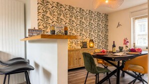 Un comedor con una mesa de madera, sillas y una pared con un diseño de hojas.