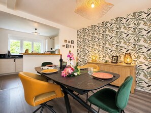 A modern dining area with a dark marble table, yellow and green chairs, and a patterned wallpaper.