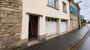 Un edificio de dos pisos con fachada de piedra, varias ventanas y entrada con tejas.