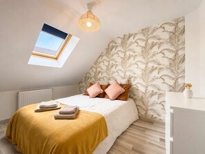 A bedroom with a bed, pillows, a bedside table, a radiator, a window, and a ceiling light. - 2-bedroom apartment, 2 bathrooms, garage, and greenway (Alençon)