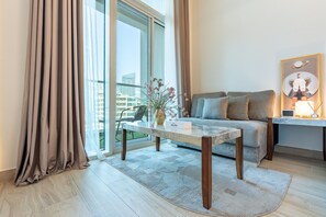 Ein modernes Wohnzimmer mit einer Couch, einem Couchtisch und Blick auf eine Stadtlandschaft durch große Fenster.