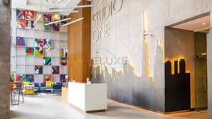 Een moderne receptiezone met een geometrisch wandkunstwerk, een receptiebalie en een lichtinstallatie van een stadsgezicht.