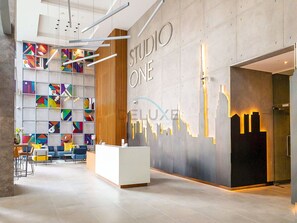 Ein moderner Empfangsbereich mit einer geometrischen Wandkunst und einer Rezeption, sowie einer Installation mit Stadtansicht-Beleuchtung.
