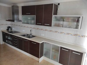 Une cuisine moderne avec des meubles de couleur sombre, un évier en acier inoxydable et un four à micro-ondes.