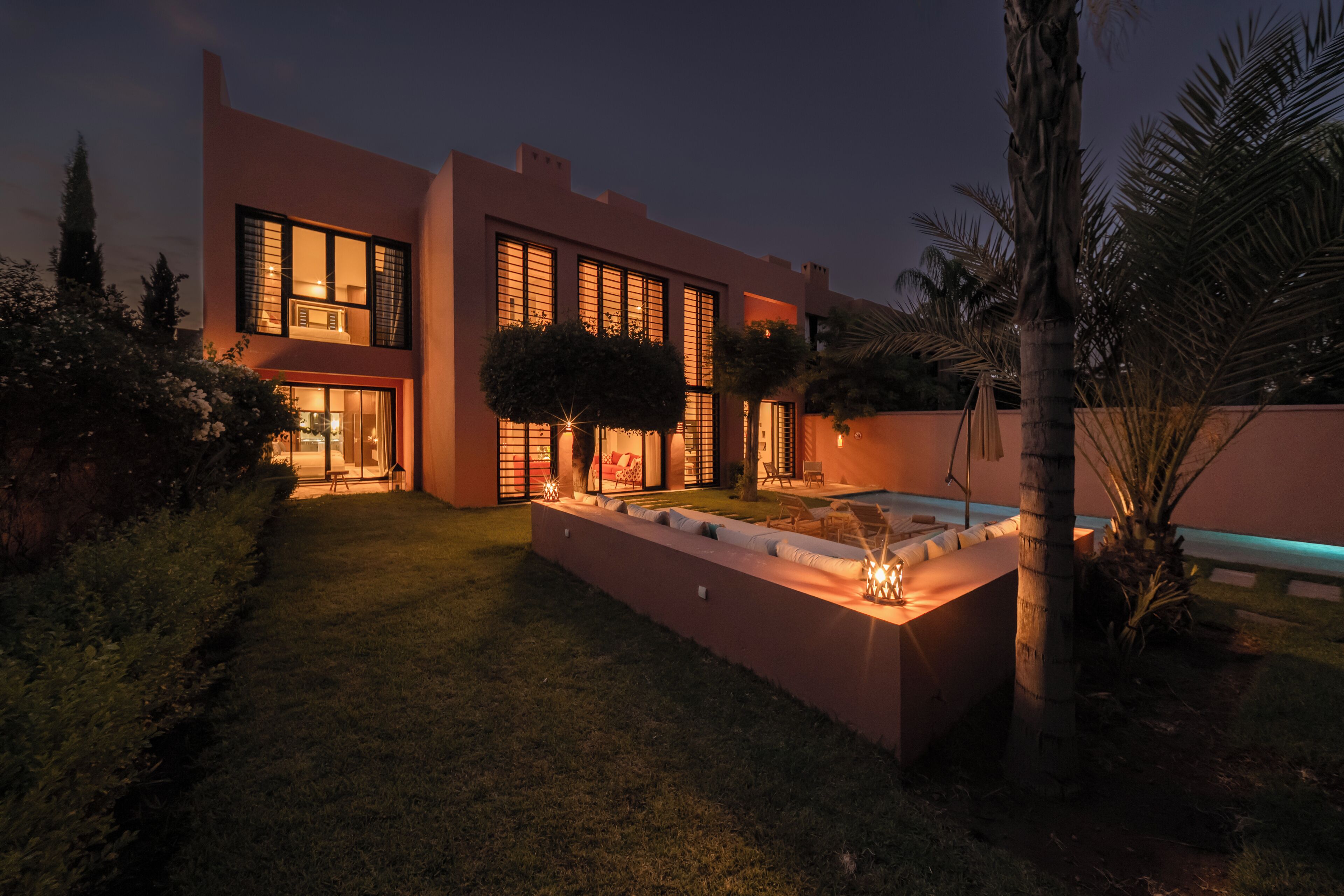 Ein modernes Haus mit gepflegtem Rasen, einem Schwimmbad und einer Terrassenfläche.