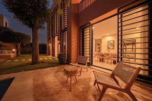 An outdoor patio with a wooden bench, a small round table, and a glass door leading to an interior dining area.