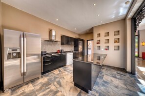 A modern kitchen with a stainless steel refrigerator, a built-in oven, and a black countertop island. - Riad Majorelle – Al Maaden Golf – Marrakech (Marrakech)