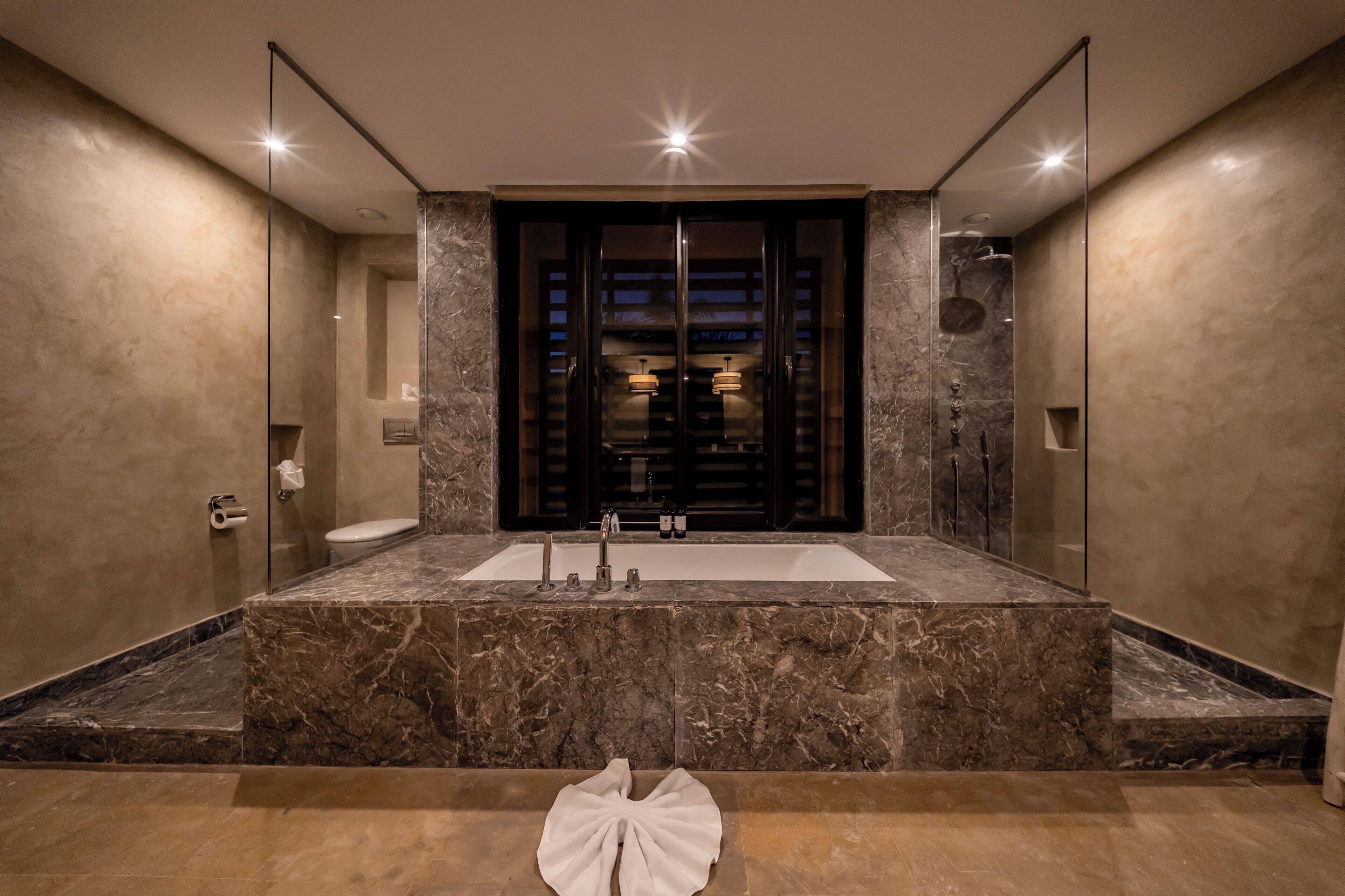 A modern bathroom with a large marble sink, a glass-enclosed shower, and a mirror above the sink.