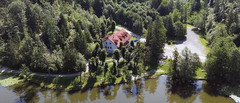 A house surrounded by dense forest and a body of water.