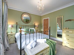 A bedroom with a four-poster bed, a chandelier, a mirror, and a dresser. - Victorian Caernarfon House for 6 (Caernarfon)