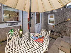 A round metal table with a bottle of wine and a magazine, under a tent-like structure. - Victorian Caernarfon House for 6 (Caernarfon)
