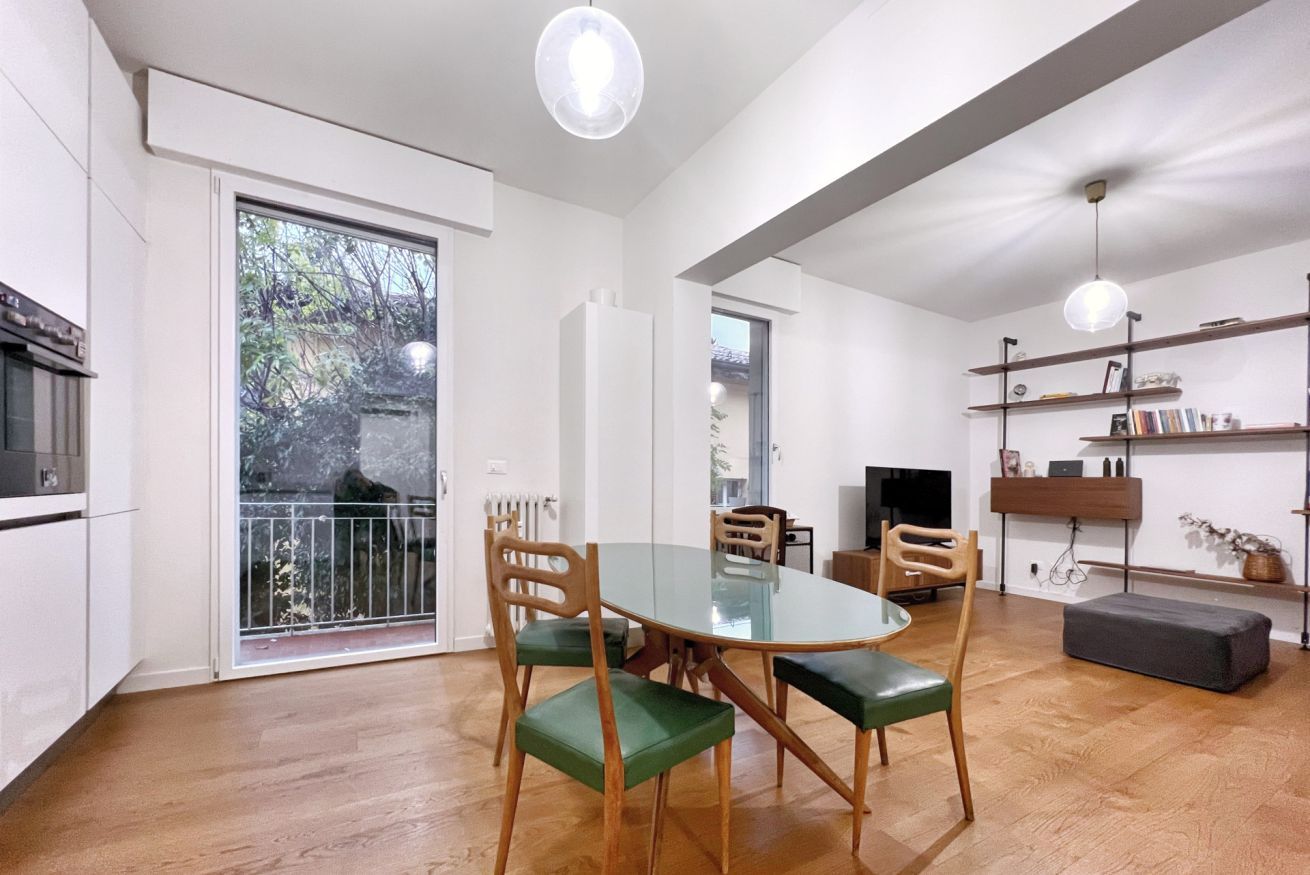 Een moderne woonkamer met een glazen eettafel, houten stoelen, een bank en een televisie.
