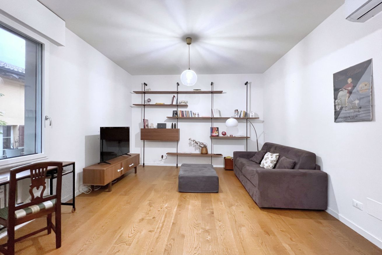 Ein modernes Wohnzimmer mit einer Couch, einem Fernseher und Holzböden.