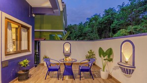 An outdoor patio with a round table and chairs, potted plants, and a view of a building with a green facade. - ELIVAAS Casa Vilson 3BHK Villa with Pool (Salvador du Mundu)
