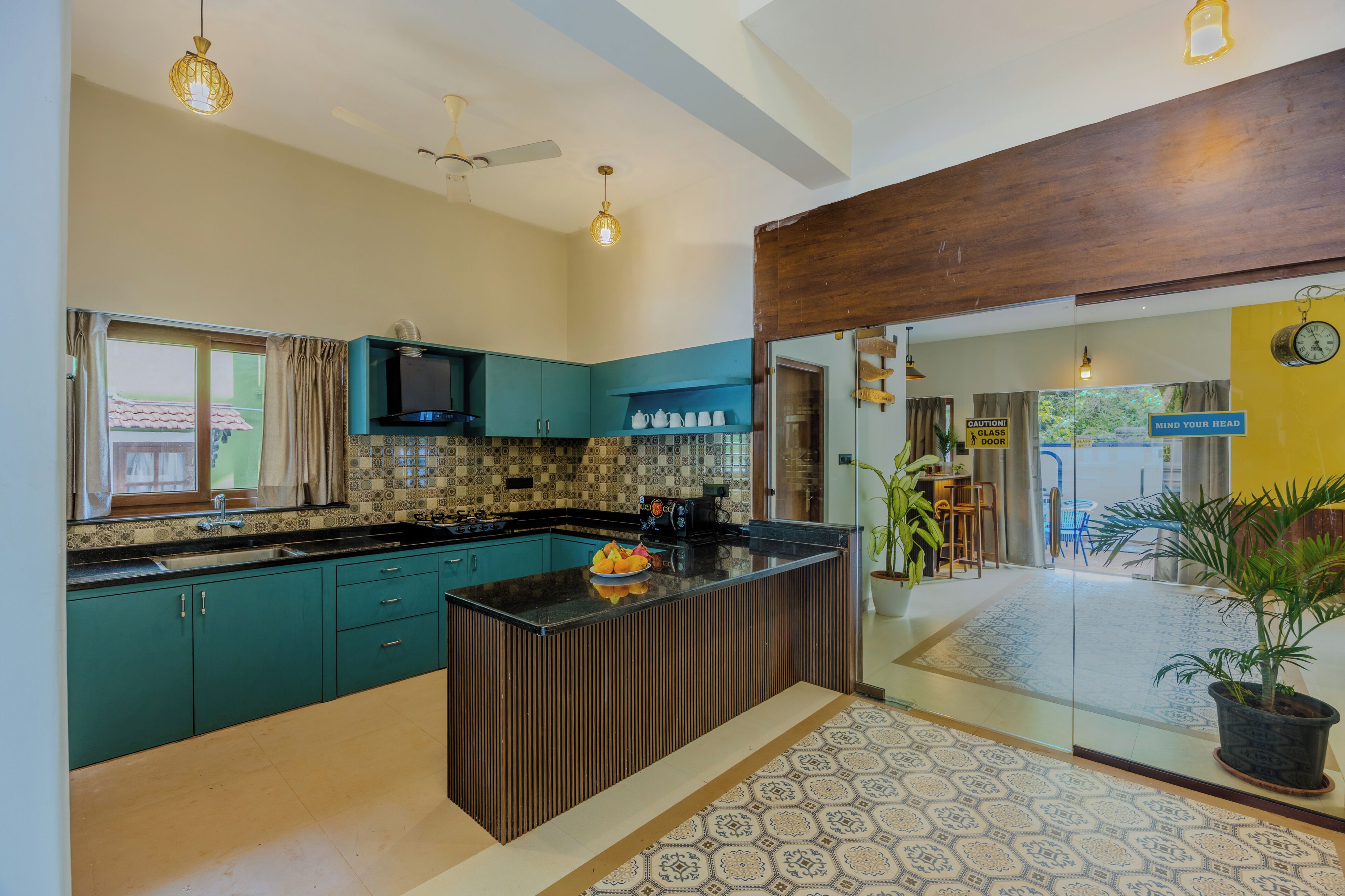 Uma cozinha moderna com armários verde-água, bancada preta e uma ilha central.
