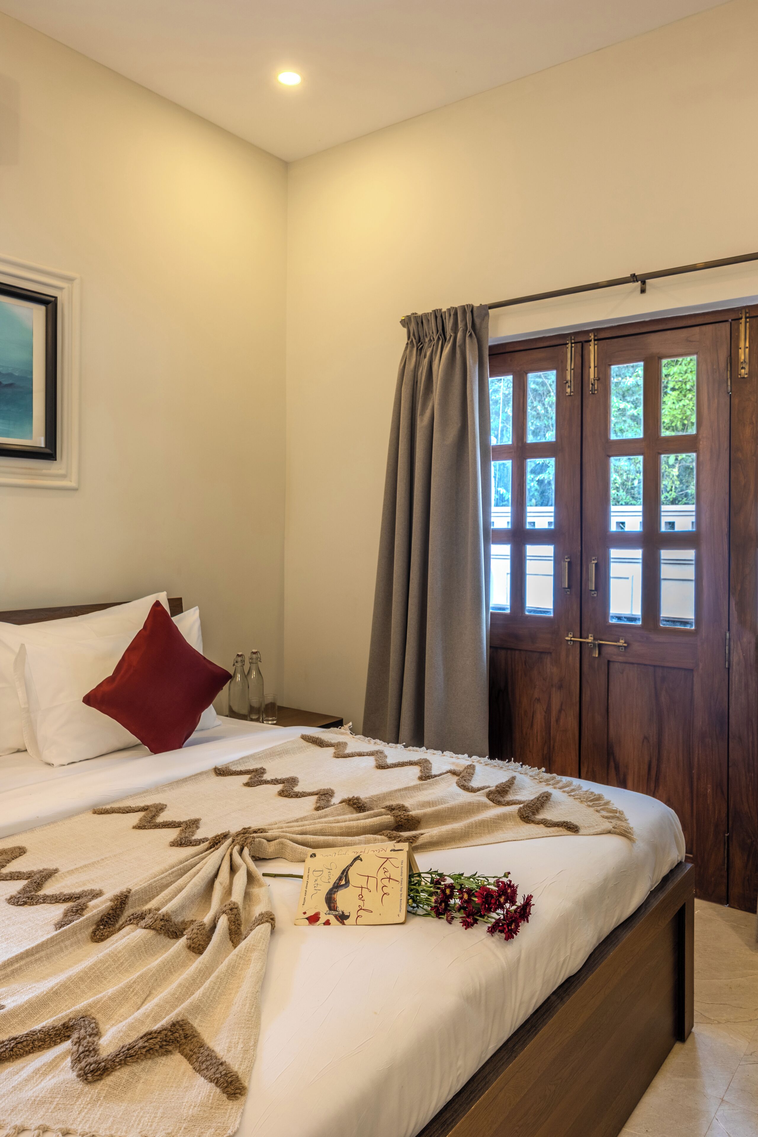 Un dormitorio con una cama grande, una puerta de madera y vistas al verdor exterior.