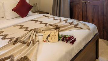 Un dormitorio con una cama grande, una puerta de madera y vistas al verdor exterior.
