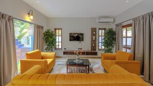 A living room with a sofa set, a coffee table, a flat-screen TV, and a potted plant. - ELIVAAS Casa Vilson 3BHK Villa with Pool (Salvador du Mundu)