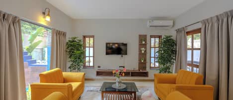 A living room with a sofa set, a coffee table, a flat-screen TV, and a potted plant.