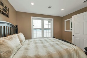 Un dormitorio con cama, ventana con vistas, puerta y pared con un letrero.