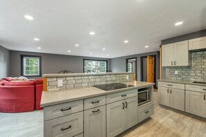 A modern kitchen with grey cabinets, a granite countertop, and a built-in stove. - NEW FOR 2027 Lake Winnipesaukee Waterfront Sleeps 16 (Moultonborough)