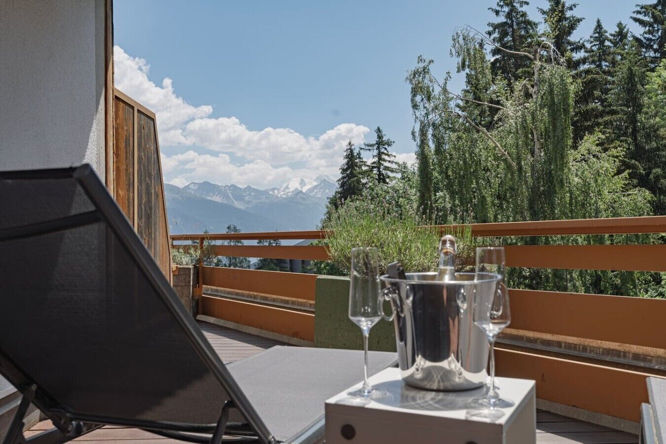Un balcon avec une table dressée pour un repas, donnant sur un paysage montagneux.