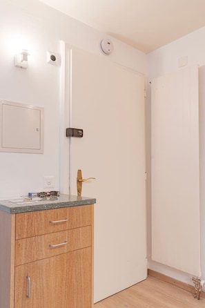 A room with a wooden cabinet, a white door, and a light switch on the wall. - Cozy Studio • Swimming Pool • View of the Alps • Crans-Montana (Crans-Montana)