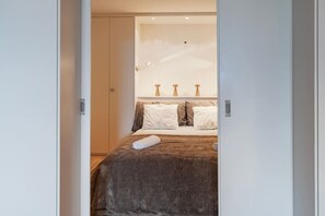 Ein Schlafzimmer mit Bett, Kissen, einem Nachttisch und einem Beistelltisch.