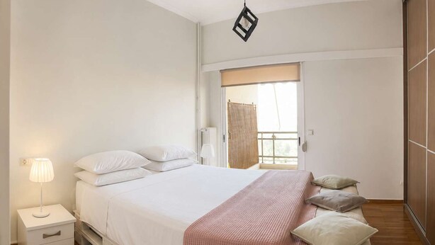 A bedroom with a bed, bedside tables, a lamp, a window with a view, and a wardrobe. - Floisvos Seaview Escape - Fully Equipped Space (Palaio Faliro)