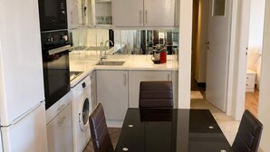 A compact kitchen with a built-in oven, microwave, and washing machine. - Floisvos Seaview Escape - Fully Equipped Space (Palaio Faliro)