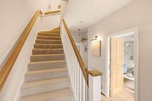 A carpeted staircase with wooden handrails leading to a landing.