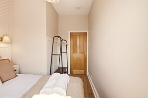Une chambre à coucher avec un lit, une table de chevet, une lampe, une armoire et une porte.