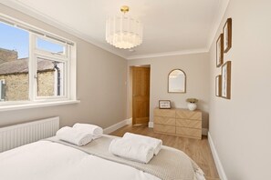 A bedroom with a bed, a dresser, a mirror, and a window. - Ember Cottage - North East Escapes (Amble)