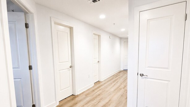Un pasillo con puertas blancas y suelo de madera.