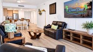 Ein modernes Wohnzimmer mit einer Ledersofa, einem Esstisch und einem Fernseher, der 'Dunn Deal Properties & Vacation Rentals' anzeigt.