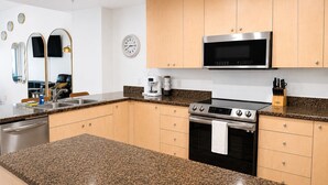 Cocina moderna con encimeras de granito, electrodomésticos de acero inoxidable y armarios de madera.