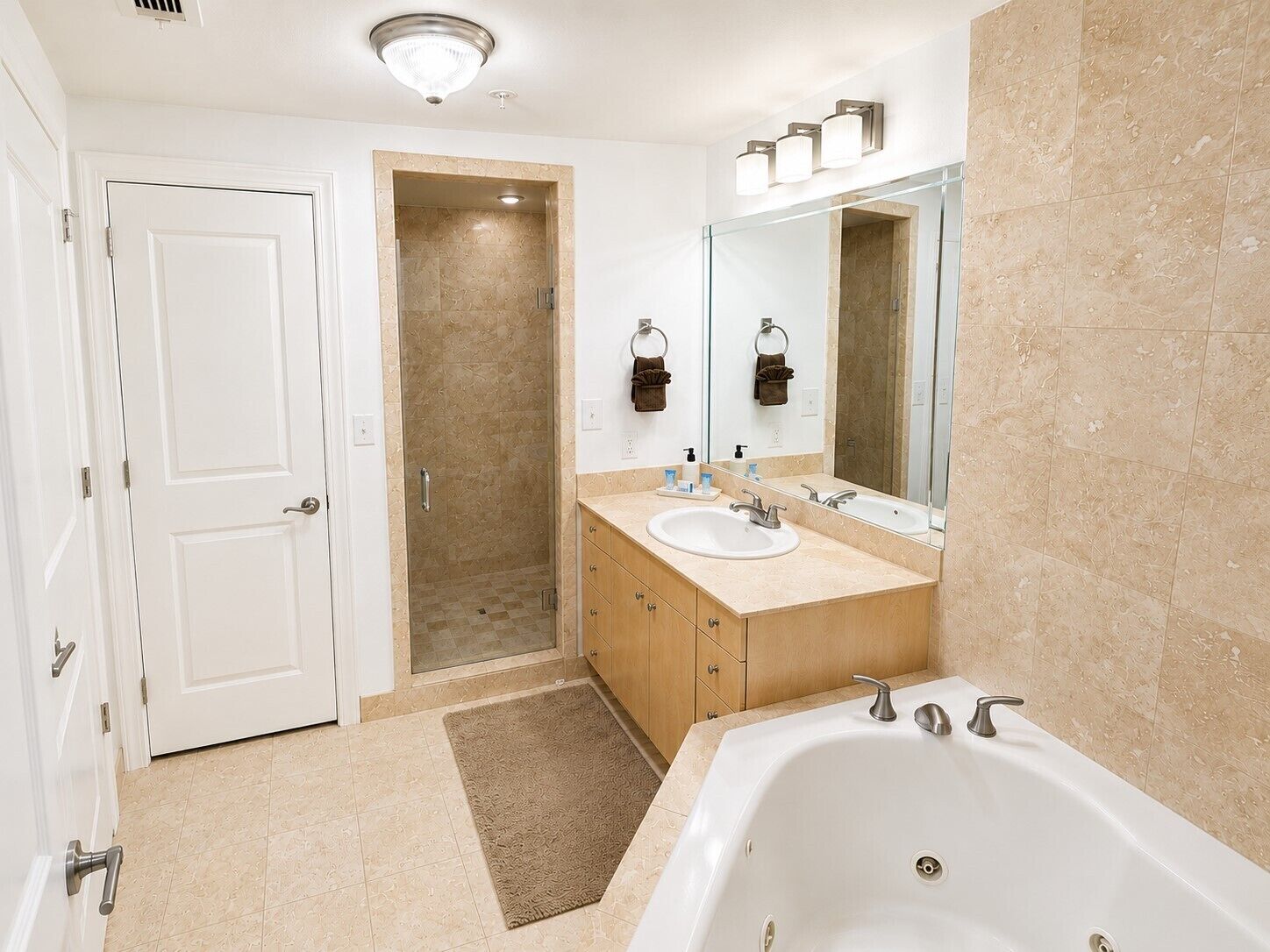 A modern bathroom with a walk-in shower, a double sink vanity, and a large bathtub.